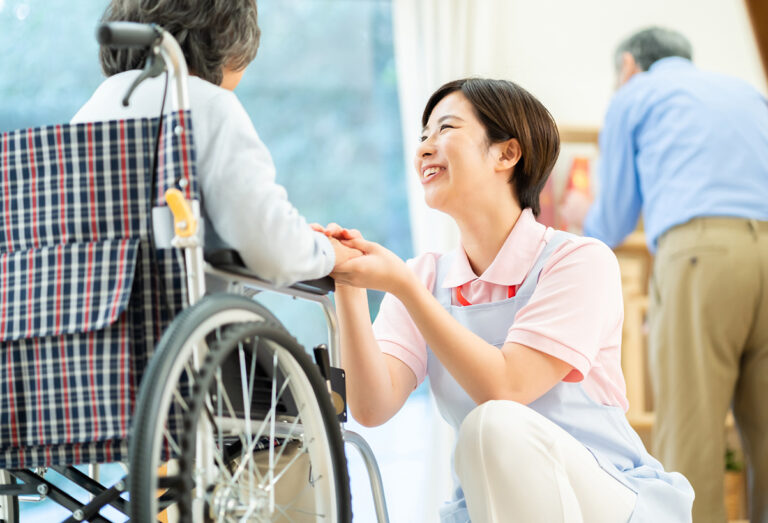 介護職員が車椅子の入居者に笑顔で支援している生活風景